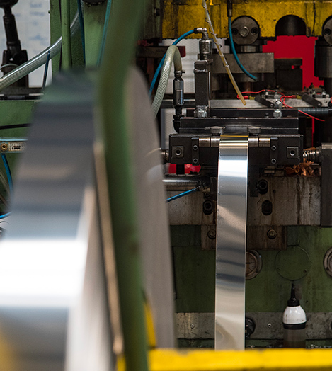 Coiled metal strip feeding a deep drawing press
